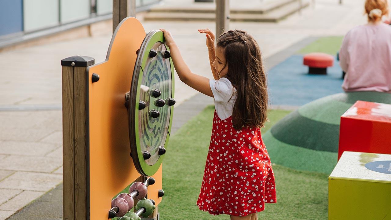 une petite fille joue avec un des équipements d'une aire de jeux inclusive